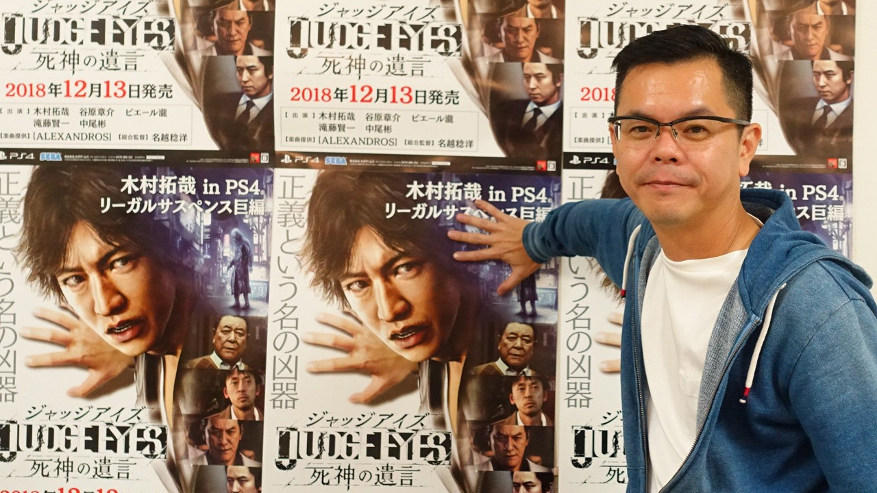 Kazuki Hosokawa de SEGA prend la pose devant une affiche japonaise de Judgment.